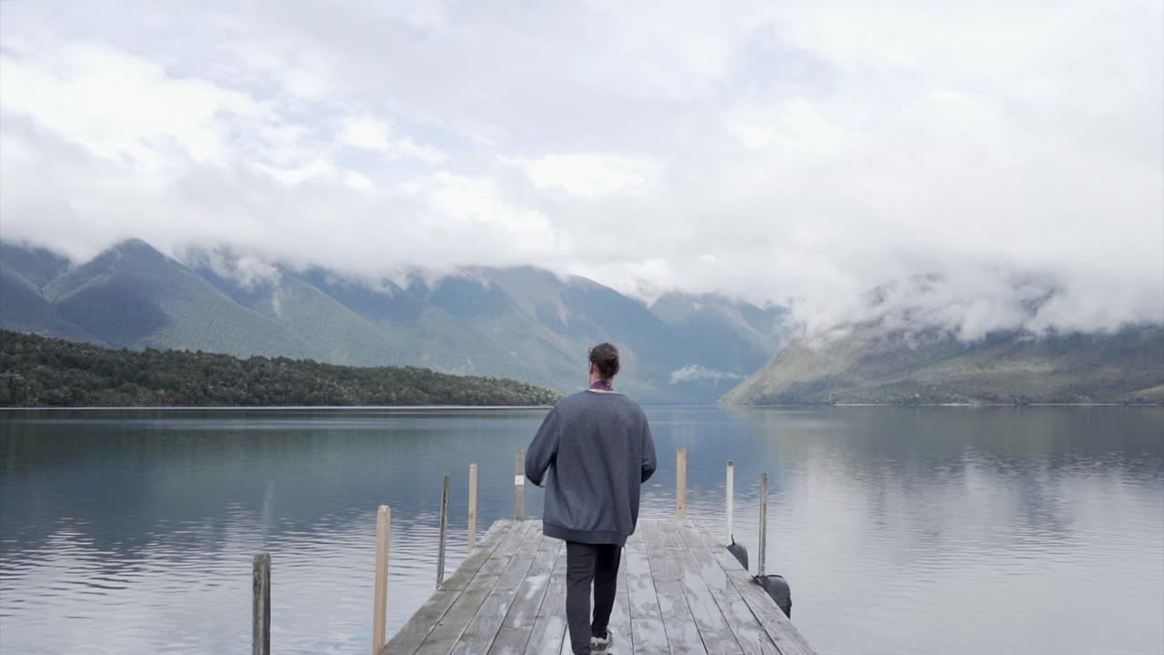 Man walking on a dock by a lake