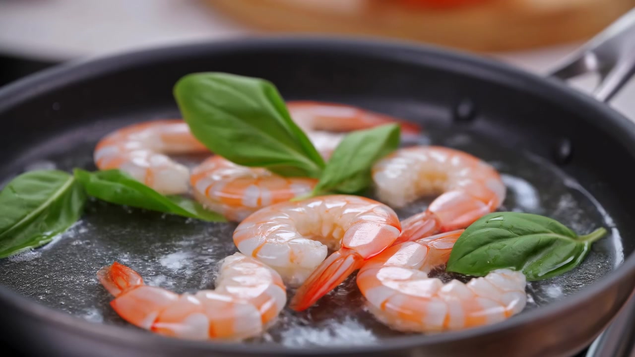 Fresh Shrimp Sizzling In Pan With Basil Leaves, Gentle Simmer Creating Glossy Orange Tails, Closeup Macro Shot