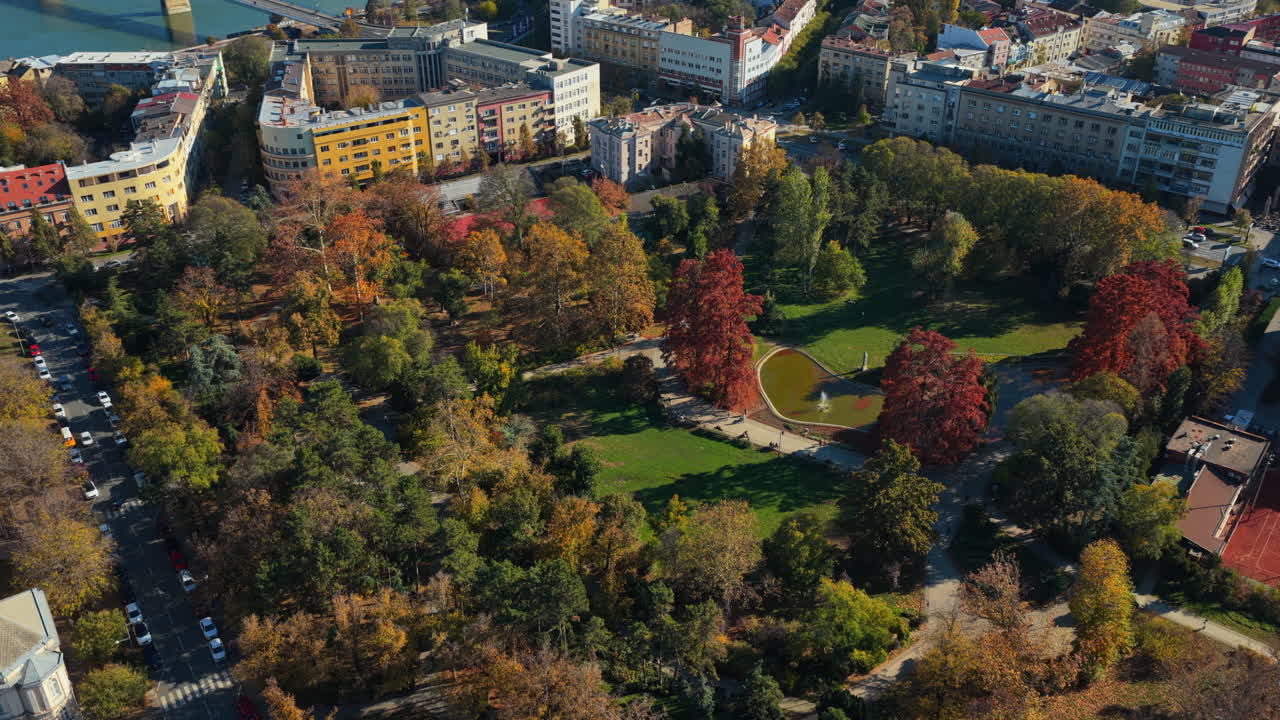 Aerial drone view of Dunavski Park in Novi Sad during autumn, with vibrant trees, walking paths, and a small pond