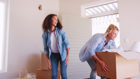 female friends carrying boxes into new home and celebrating on moving day