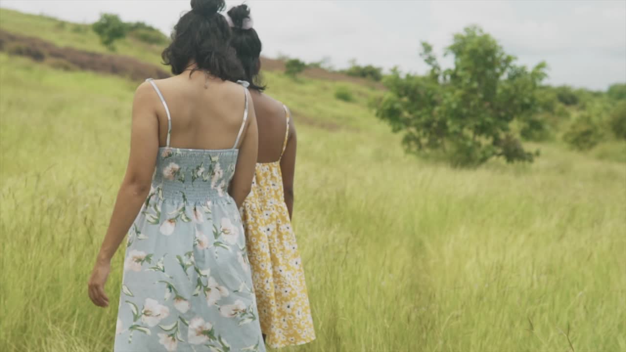 들판에서 멀리 걸어가는 두 명의 인도 소녀