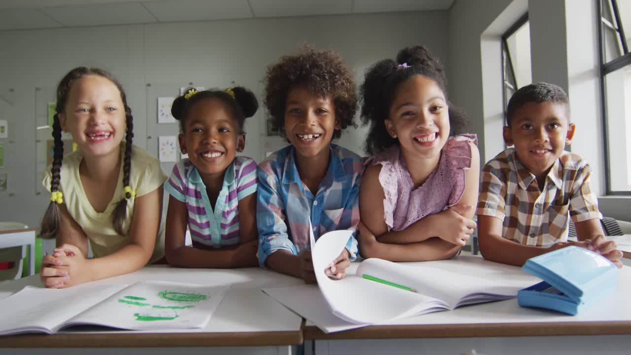 Video of happy diverse pupils learning together in classroom