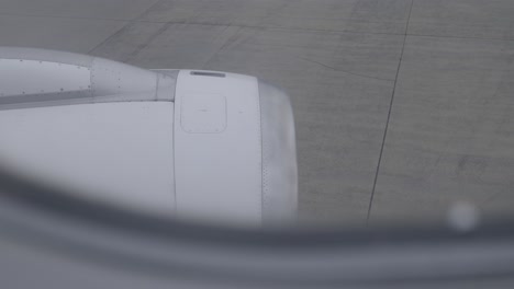 Airplane engine view from passenger window while taxiing on airport runway