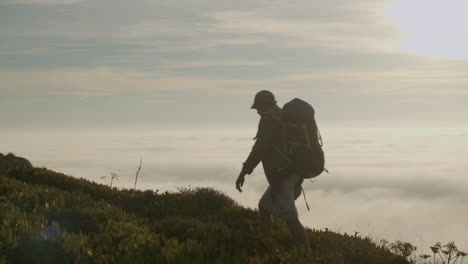 excursionista senior parado en la cima de la montaña al atardecer y disfrutando del paisaje