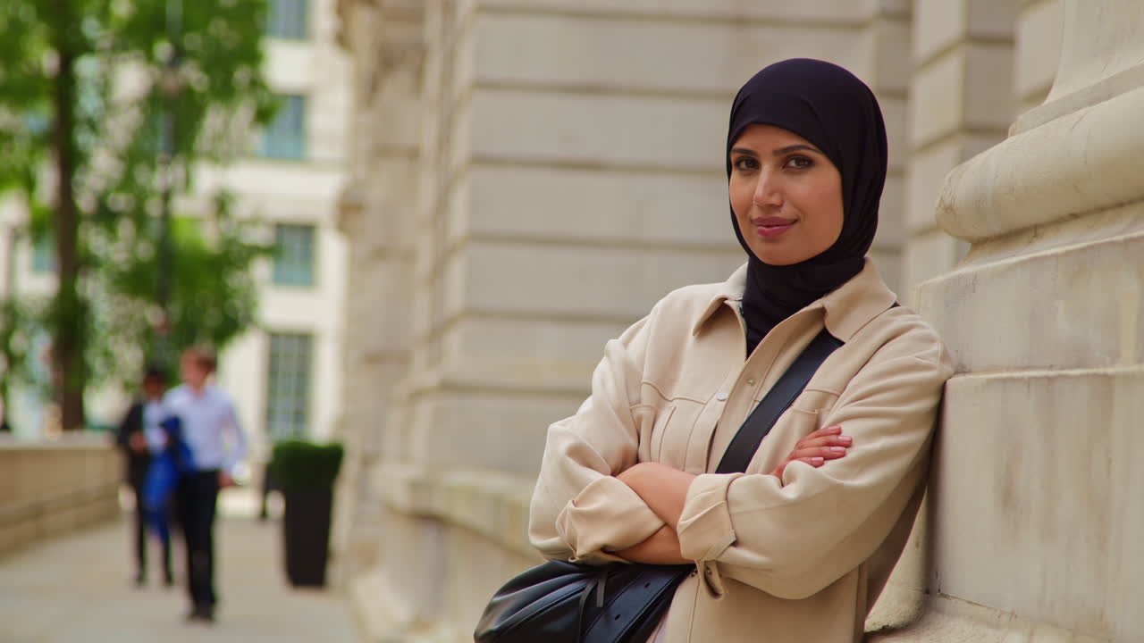 Portrait Of Smiling Muslim Businesswoman Wearing Hijab And Modern Business Suit Standing Outside City Office Buildings