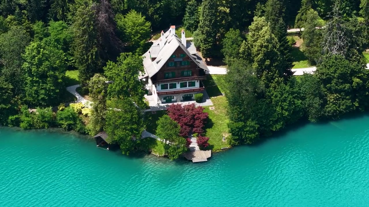 Ripresa con drone di una villa sul lago e del paesaggio bagnato dalle acque blu glaciali del Lago di Bled, Slovenia