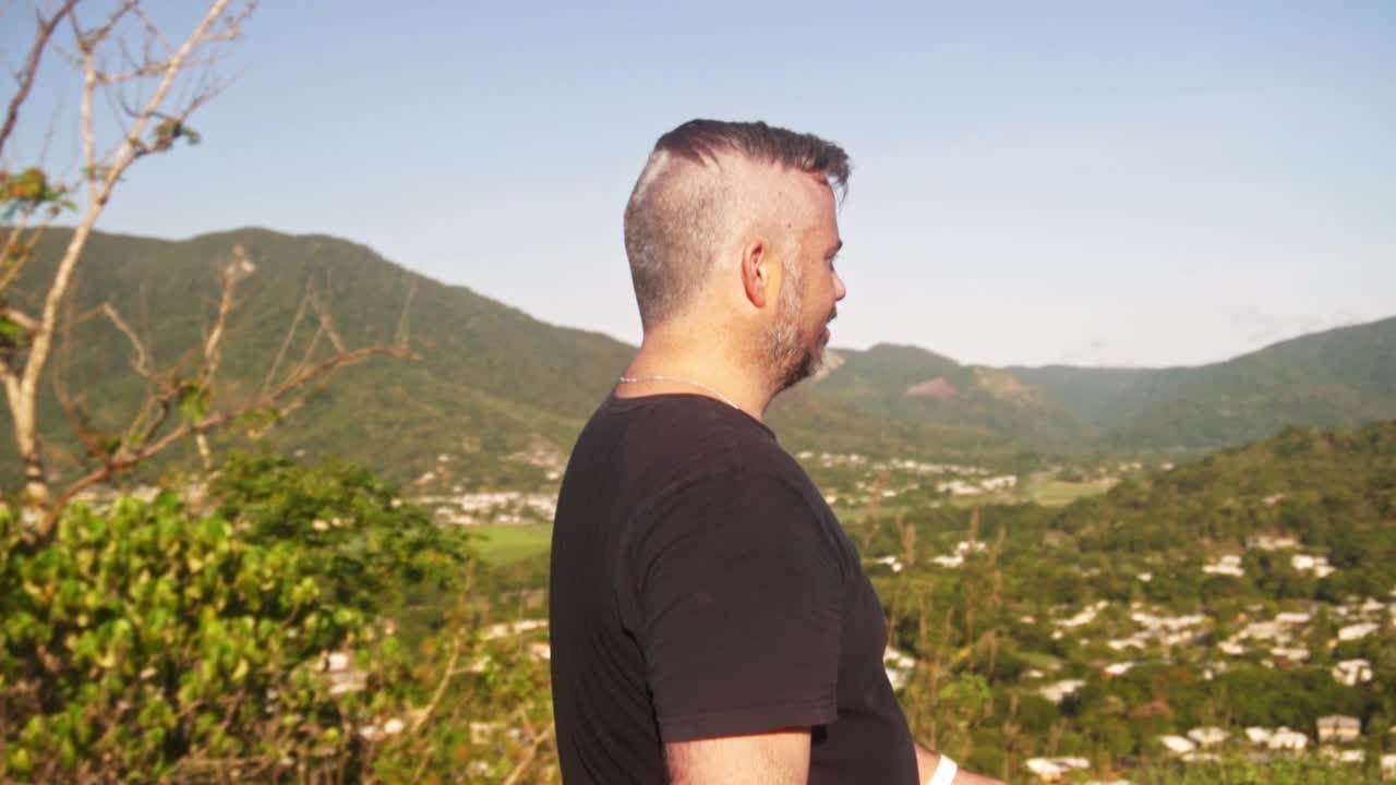 slow motion shot of man walking along the top of a nature walk.
