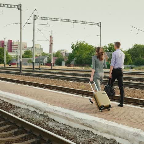 Two-Businessmen-With-Luggage-Go-Along-The-Railroad