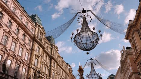 Elegant chandeliers hanging over Graben Street with historic buildings in Vienna, Austria