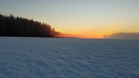 Time-lapse-of-beautiful-frozen-lake-in-Finland-filled-with-mist-fog-during-sunset,-dreamlike-moment-in-Finnish-Lapland