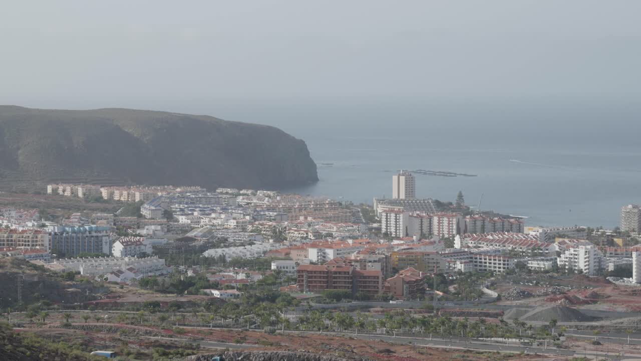 View of a village by the ocean on a sunny day in Los Cristianos, Tenerife, Canary Islands, Spain.