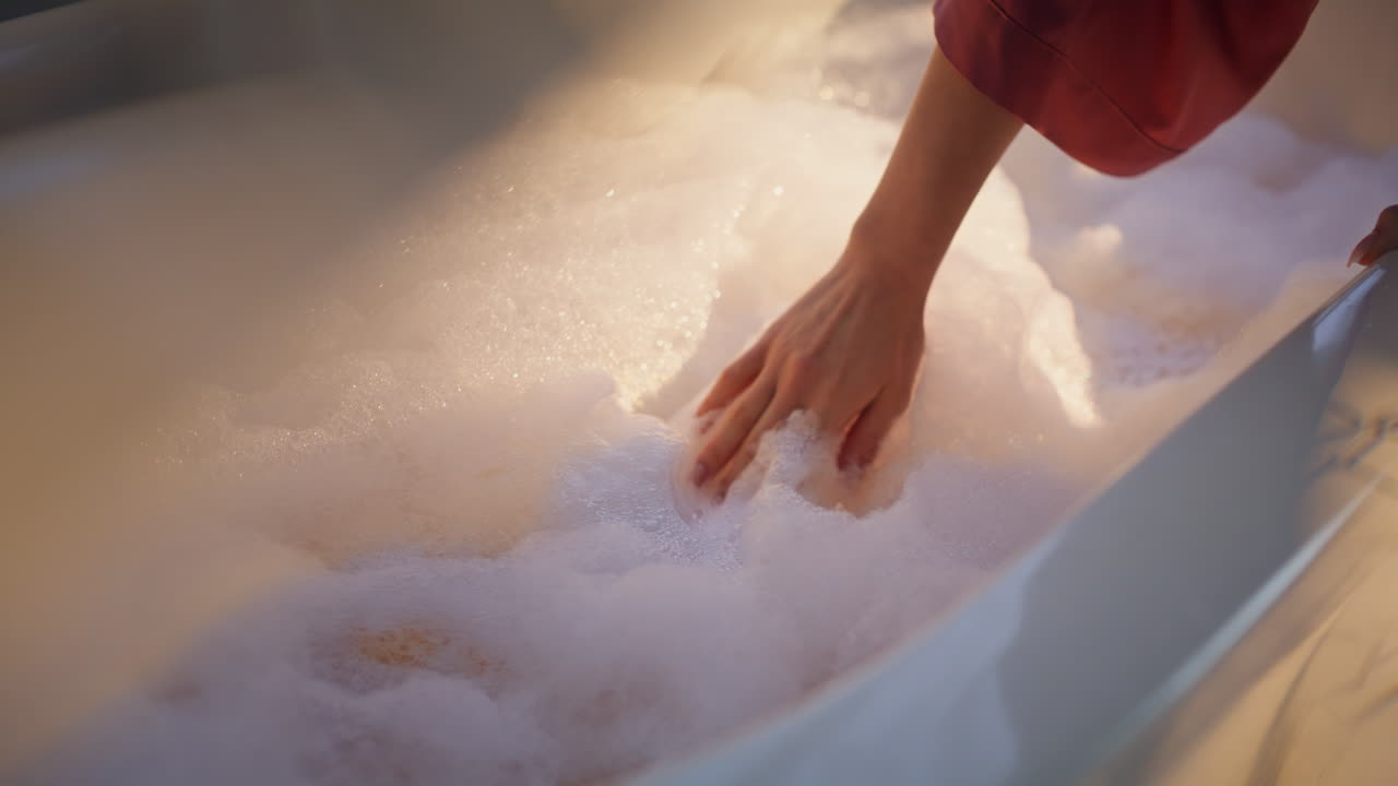 Donna in spa che tocca bolle di schiuma bianca, godendosi la routine di cura del corpo mattutina, primo piano
