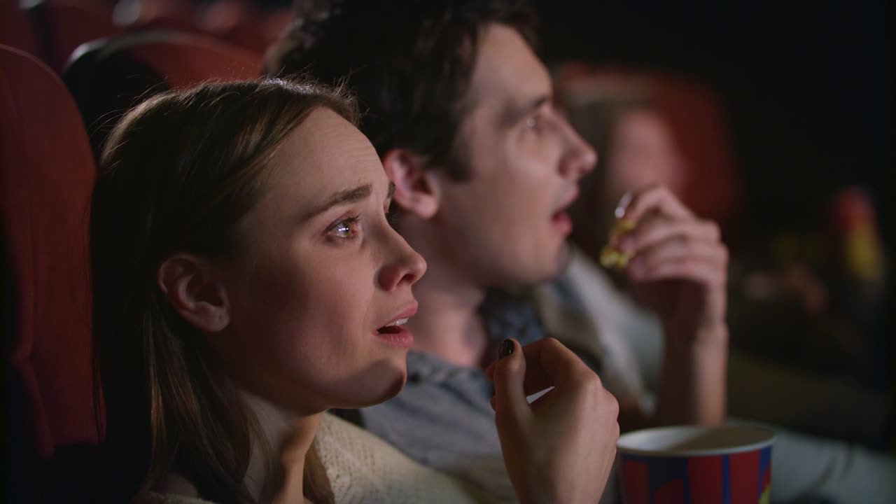 una pareja joven disfrutando de una película en el cine. una pareja comiendo palomitas de maíz y viendo una película