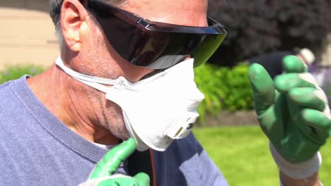 Landscaper-putting-on-a-mask-and-a-straw-hat-before-starting-his-job