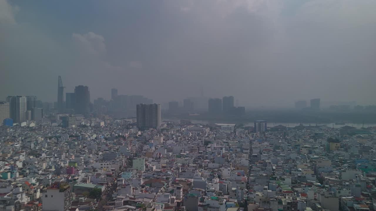 Aerial view of Ho Chi Minh City skyline with high density urban area in foreground with dramatic morning sky. Big reverse panning reveal of canal, river and skyline.