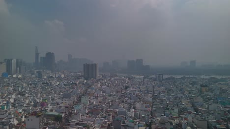 aerial view of ho chi minh city skyline with high density urban area in foreground with dramatic morning sky. big reverse panning reveal of canal, river and skyline.