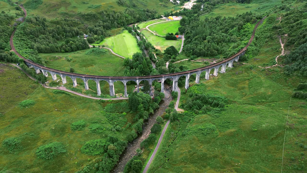 Aerial: Glenfinnan Viaduct and Loch Shiel during the day at Glenfinnan, in the Lochaber district of north-western Scotland, UK, pull out tilt up drone shot