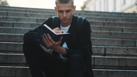 Young student writing notes outdoors.