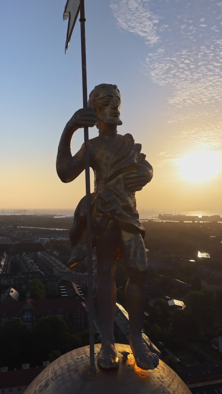 Aerial drone view of the golden statue atop a sphere on the Church of Our Saviour overlooking the Copenhagen skyline, with Frederik's Church dome in the background in Denmark. Vertical
