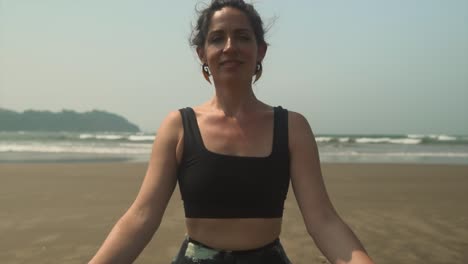 Pretty-Brunet-Woman-Meditating-at-a-Calm-beach,-Smiles-Slowmo