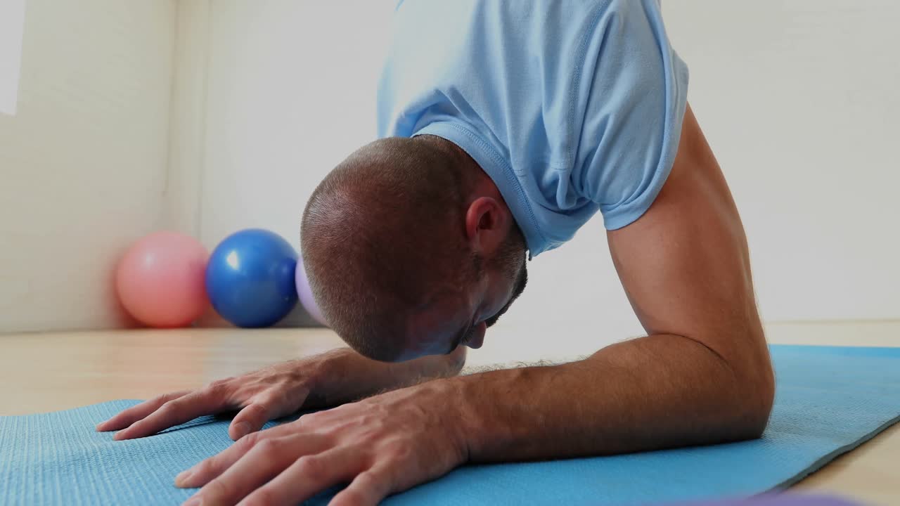 Mann trainiert auf Matte im Fitnessstudio 4K