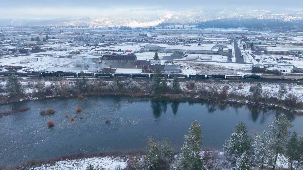 vista aérea empujando sobre un río y hacia un tren con nieve cubriendo el suelo circundante