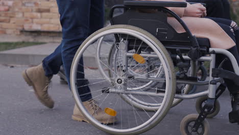 mujer y hombre paseando con sus amigos discapacitados en silla de ruedas por la ciudad