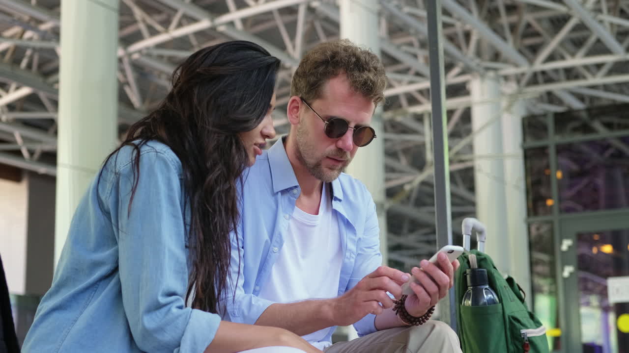 pareja mirando un teléfono en el aeropuerto