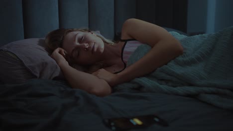 woman lying in bed with smartphone at night