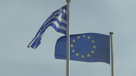 Greek-and-European-flags-fluttering-against-a-blue-sky