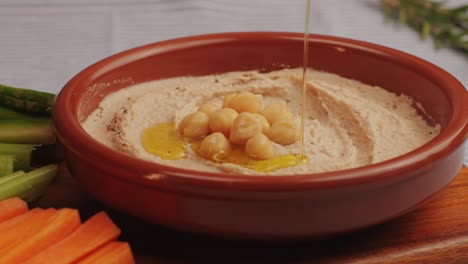 hummus among fresh vegetables on table close-up. pouring vegetables slice in hummus. hummus or fava, a healthy snack of legumes and chickpeas. kosher healthy vegan food. lean, vegetarian dish. high quality 4k footage