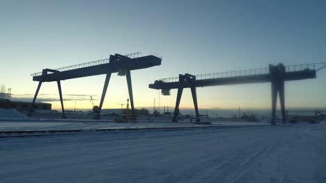 industrial cranes in a snowy landscape at sunrise/sunset