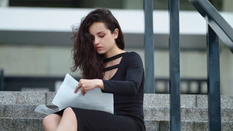 Mujer-De-Primer-Plano-Leyendo-Documentos-En-La-Calle.-Mujer-Sentada-Con-Papeles-Afuera