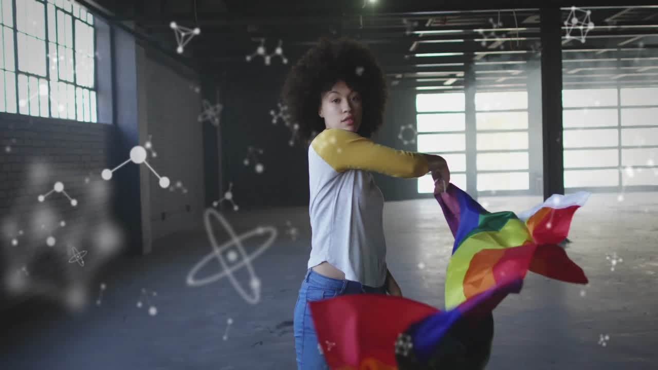 Woman turning in warehouse, wrapping in pride flag with floating science network animation
