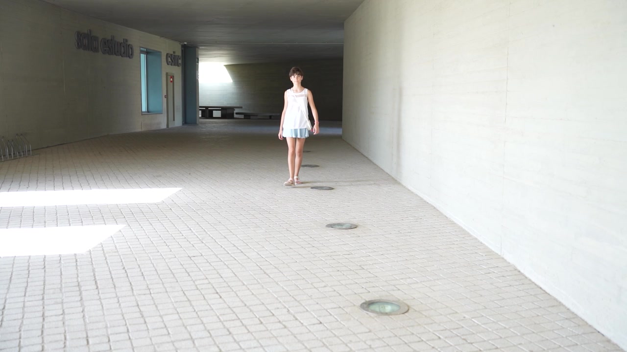 Uno spazio interno minimalista con abbondante luce naturale e una persona che cammina con grazia.