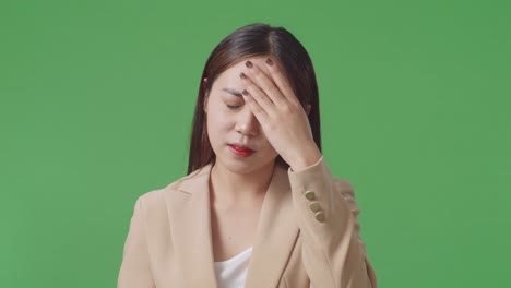 close up of asian business woman having headache while standing in front of green screen