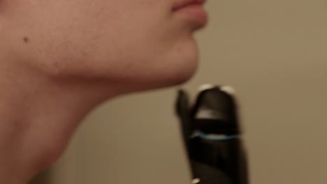 primer plano de un joven que se corta el bigote y el vello de la barbilla