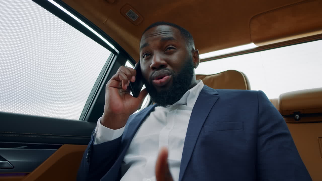 진지 한 아프리카 사업가 가 휴대전화 로 전화 하고 있다. 사람 은 자동차 의 창문 을 보고 있다