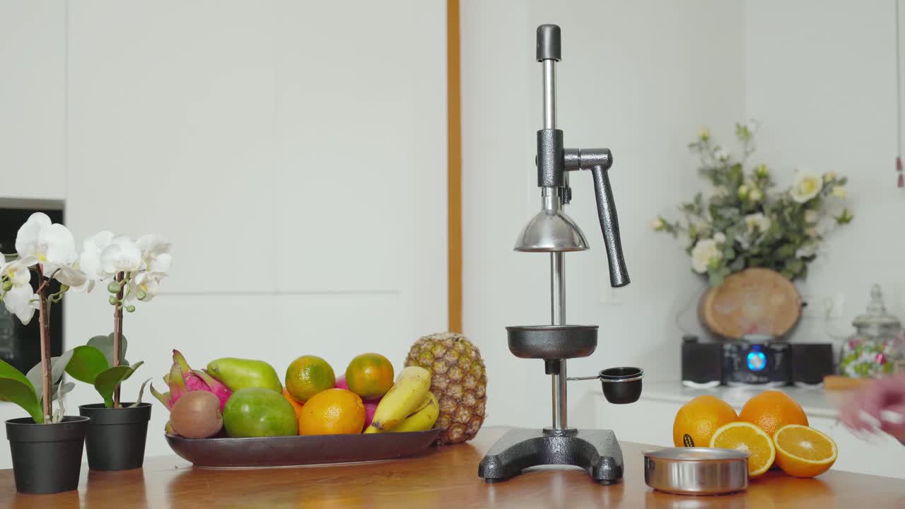 Caucasian female preparing hand press fruit juicer to make fresh orange juice