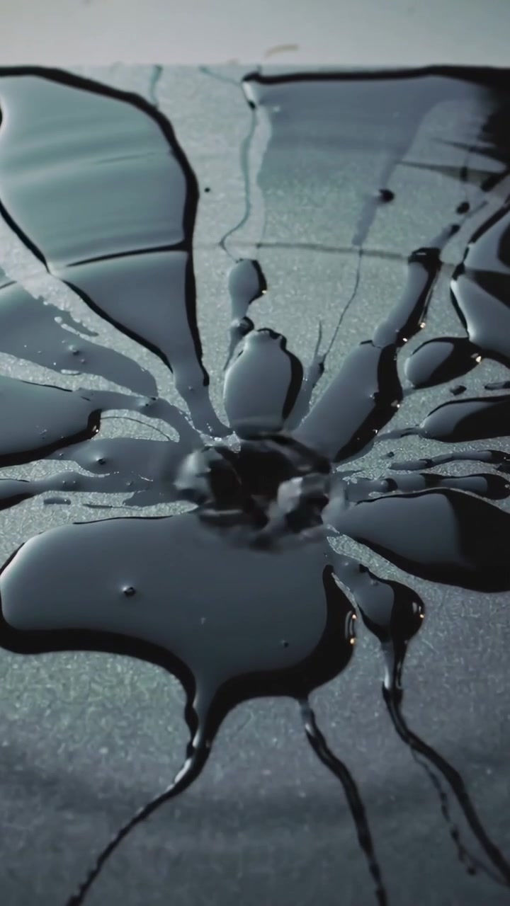 Video verticale: Goccia che colpisce un liquido viscoso, formando uno schizzo radiale su un pannello da studio con riflessi