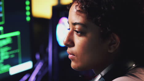 female teenage hacker sitting in front of computer screens bypassing cyber security