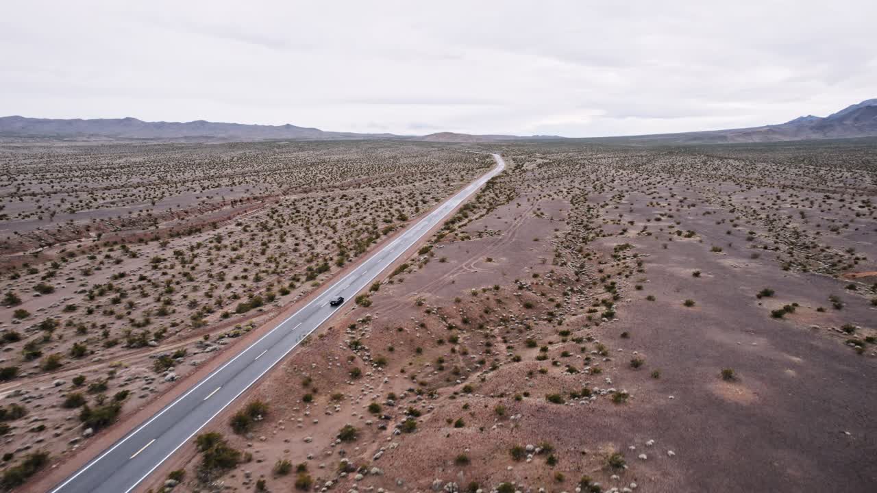 Aerial Drone Shot of a Car Driving on a Long Isolated Road in the Desert