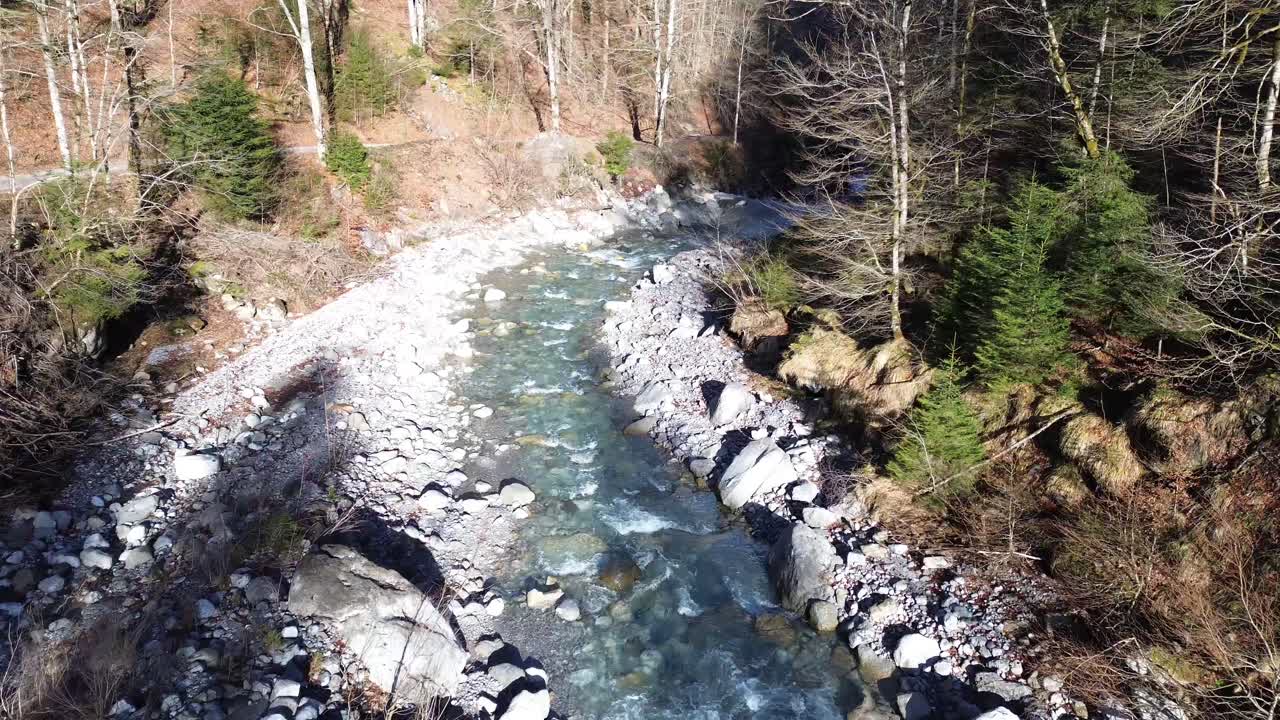 Drone che segue una strada di montagna con un fiume cristallino accanto in Austria, Europa