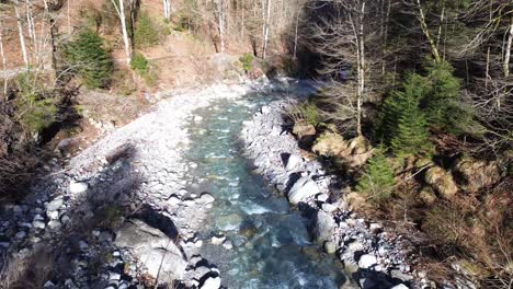 drone following mountain road with crystal clear river next to it in europe austria