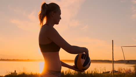 chica atlética jugando voleibol de playa salta en el aire y golpea la pelota sobre la red en una hermosa noche de verano. mujer caucásica anota un punto.