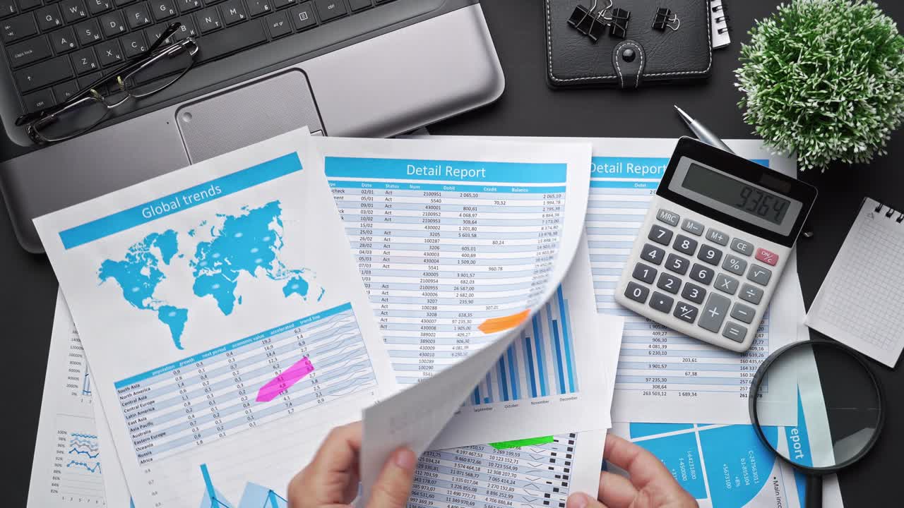 Top view of businessman's hands working with financial reports. Modern black office desk with laptop, notebook, pencil and a lot of things. Flat lay table layout.