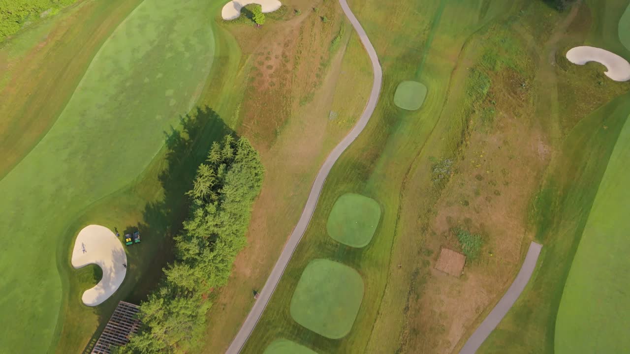 Top-down aerial shot of a golf course showing fairways, greens, bunkers, and winding cart paths, highlighting course design patterns and manicured turf