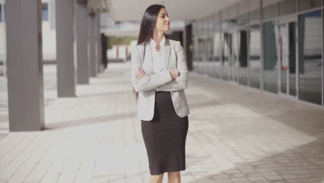 Hopeful-woman-with-folded-arms-near-building