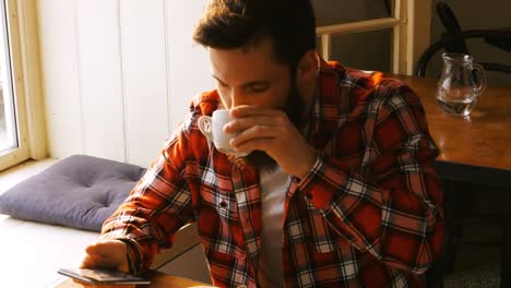 man using mobile phone and having coffee