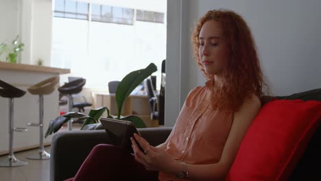 vista lateral de una joven mujer de negocios caucásica trabajando en una tableta digital en una oficina moderna 4k
